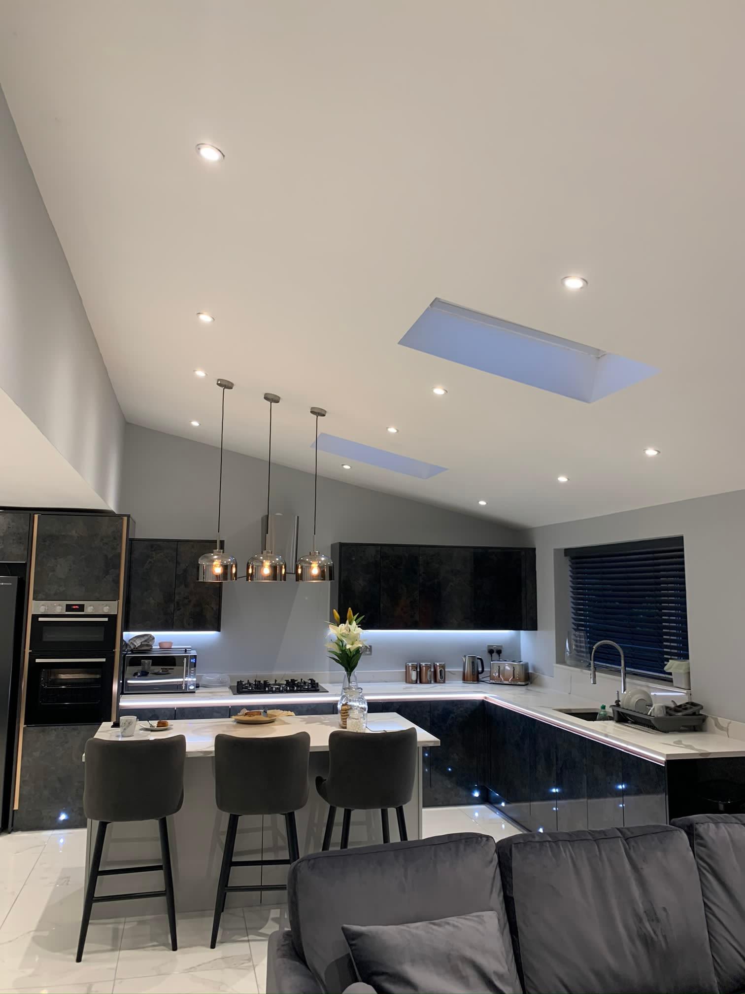 Open-plan kitchen fitted with recessed spotlights, pendant lights and warm under-cabinet LED strip lighting by DJF Electrical