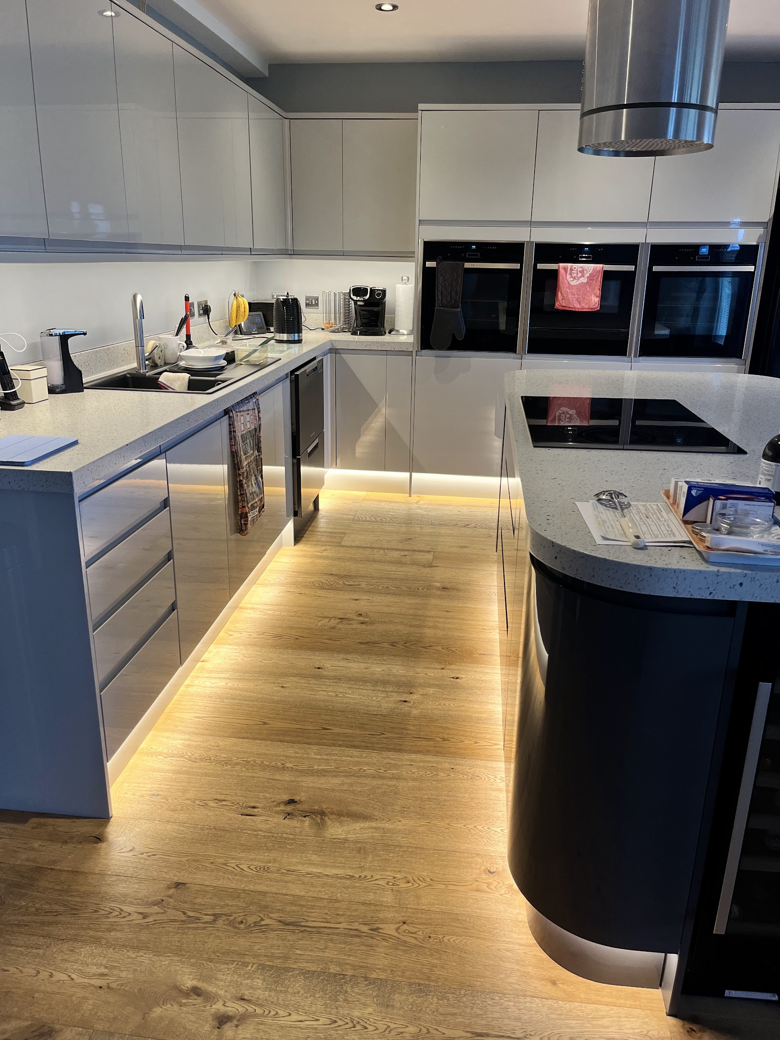 Modern grey kitchen with warm LED strip lighting glowing under the units and along the floor, installed by DJF Electrical