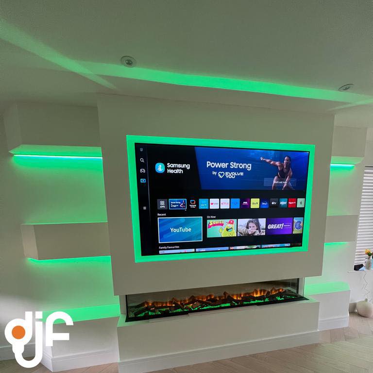 Living-room media wall with a wall-mounted TV framed by colour-changing LED strip lighting and an inset flame fire