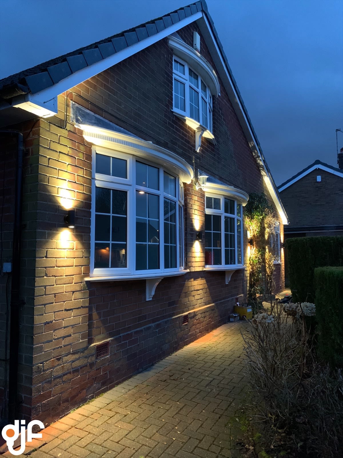 Brick house frontage at night with warm wall uplighters and downlighters picking out the windows and brickwork